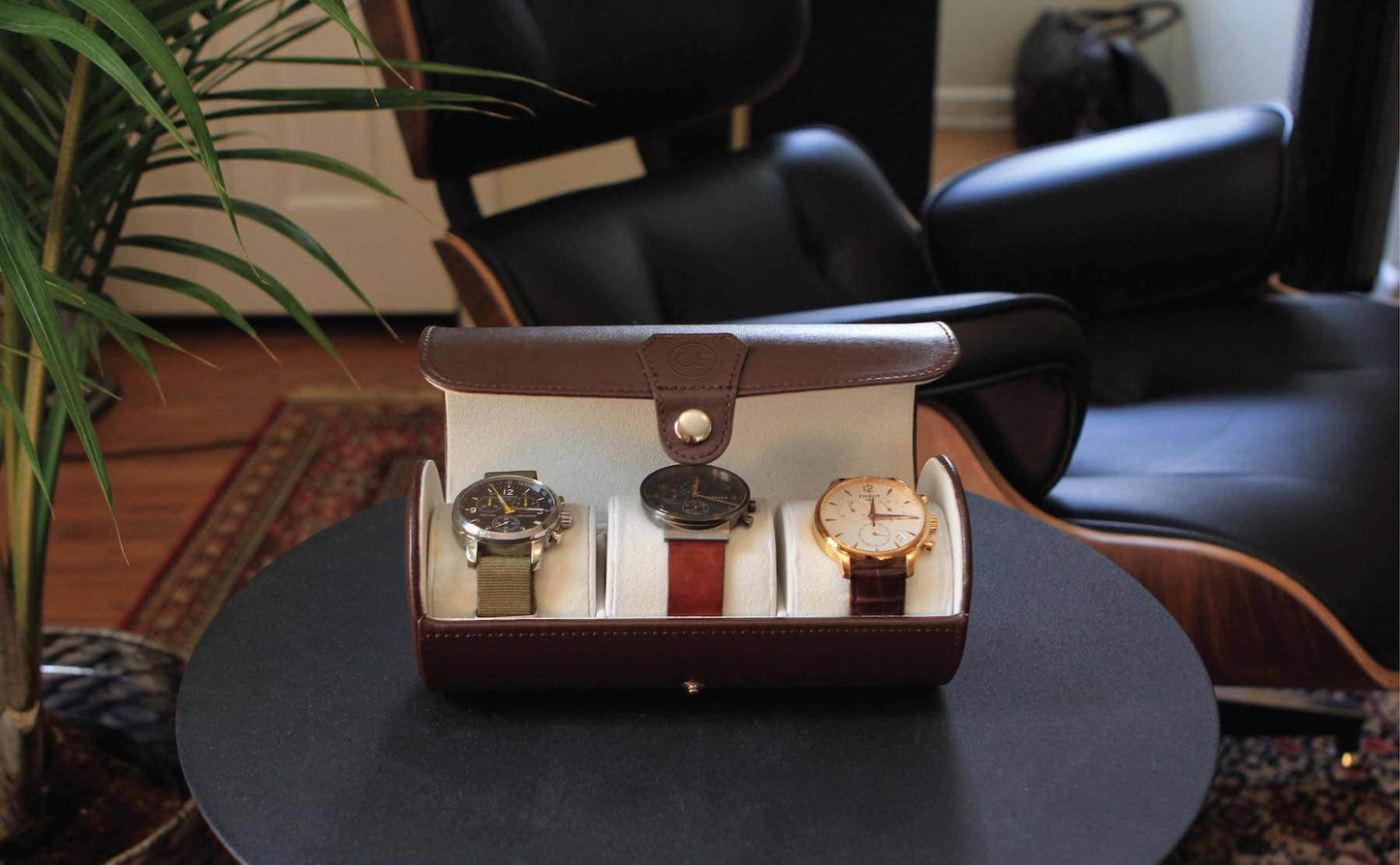 vegan leather travel watch case displaying three stylish watches on a round table in a modern living space.