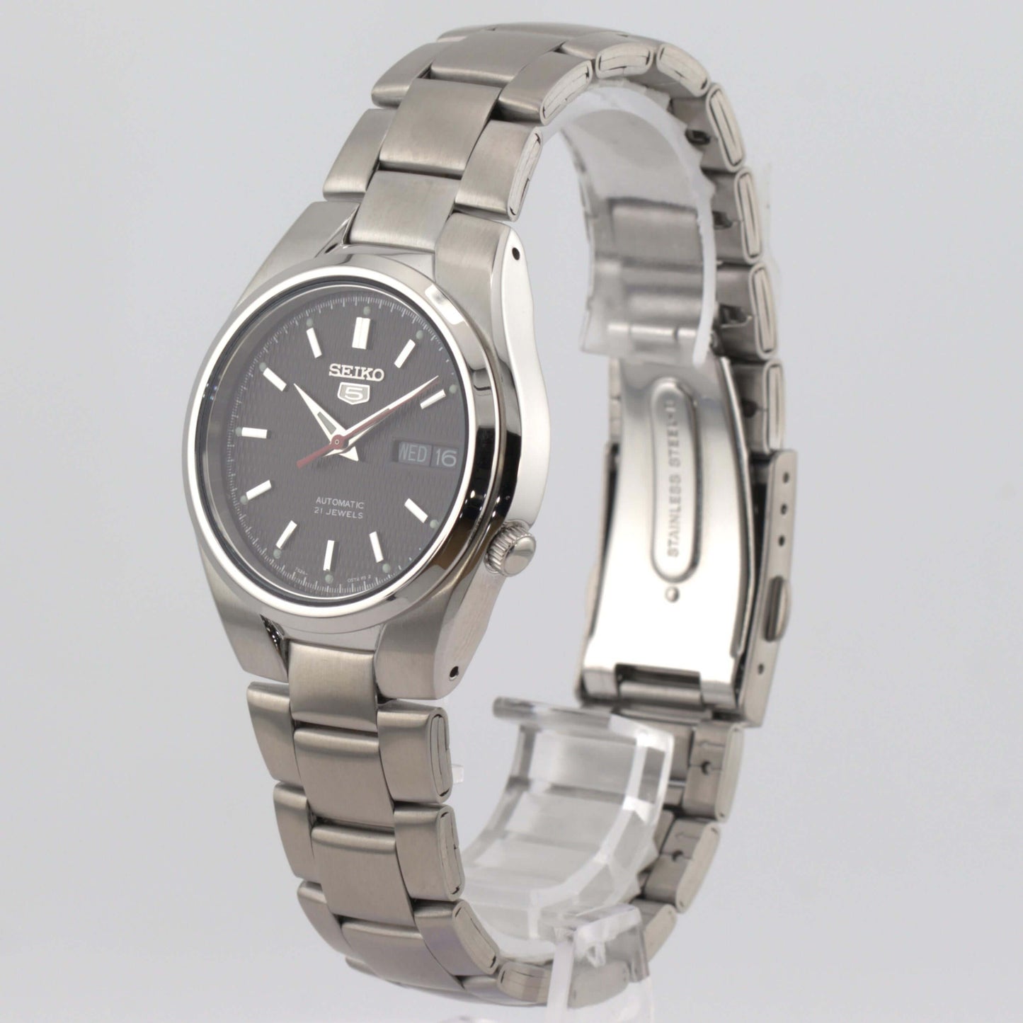 Seiko 5 automatic watch SNK607K1 displayed on a transparent stand with a black dial and stainless steel bracelet.