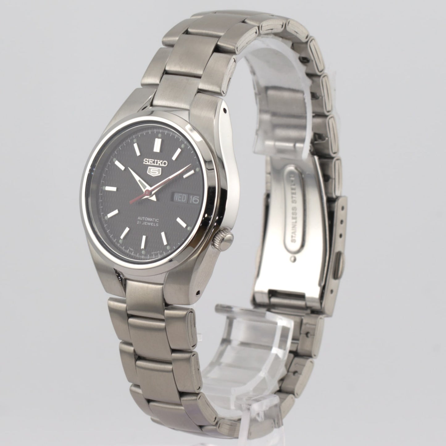 Seiko 5 automatic men's watch with black dial and stainless steel bracelet, displaying date and day features.